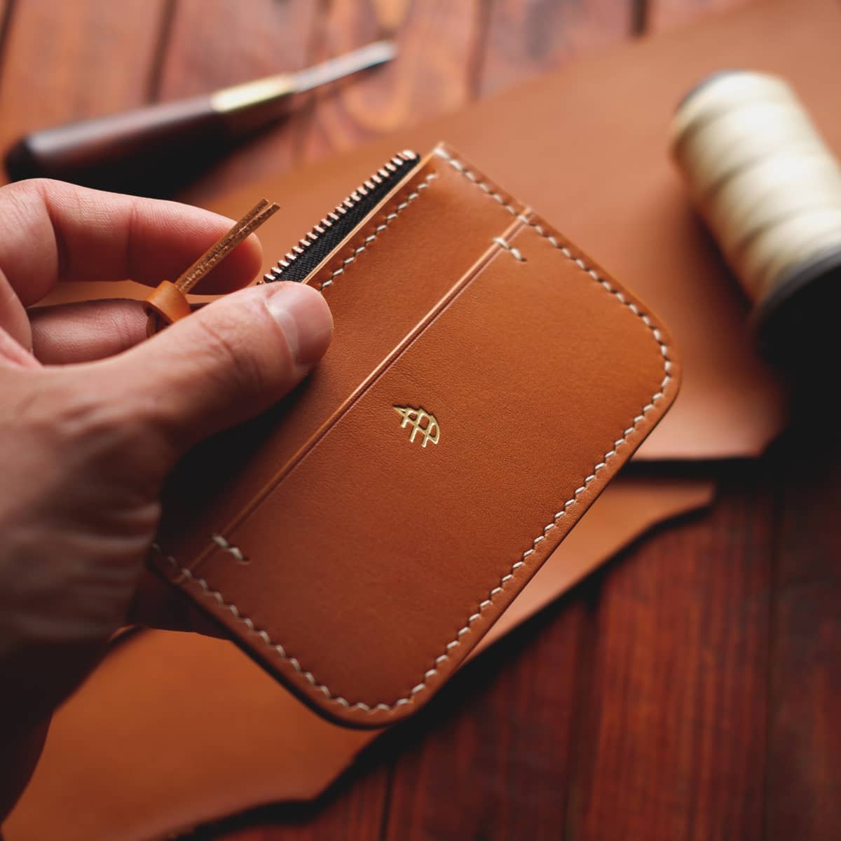 The Coulter Zipper Wallet in premium light brown aniline veg tan leather held in hand