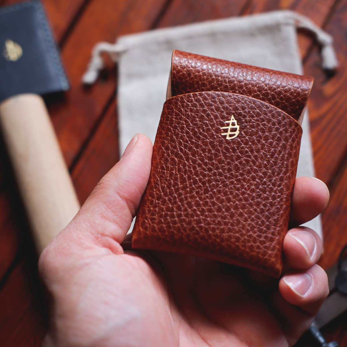 The Mini Lodgepole Stitchless Wallet in Brandy Dollaro leather held in hand - front side