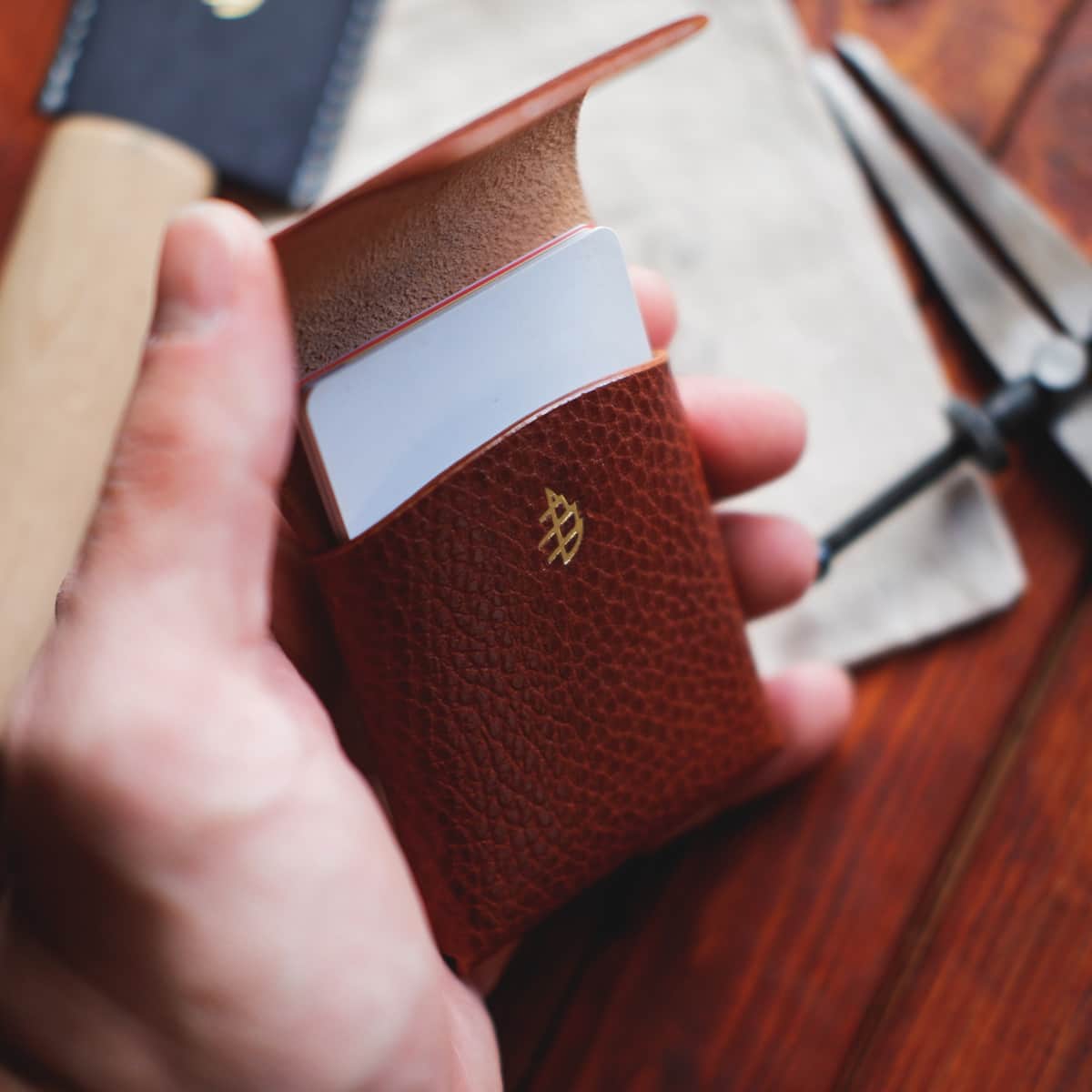 The Mini Lodgepole Stitchless Wallet in Brandy Dollaro leather held in hand with credit cards inside