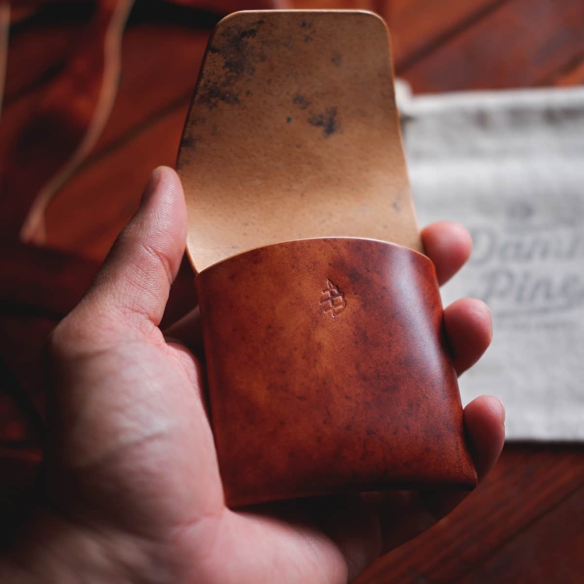 The Lodgepole Stitchless Wallet in Cognac Marbled Shell Cordovan leather held in hand with opened flap