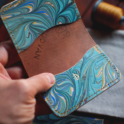 The Monterey Slim Bifold held in hand, showing the hand dyed marbled interior pockets
