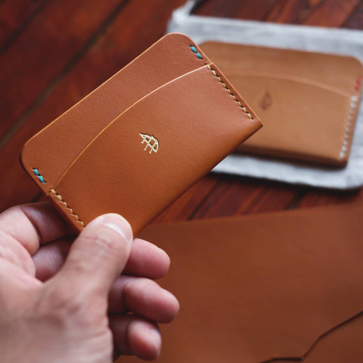 The Mountain Card Holder in light brown aniline vegetable tanned leather held in hand