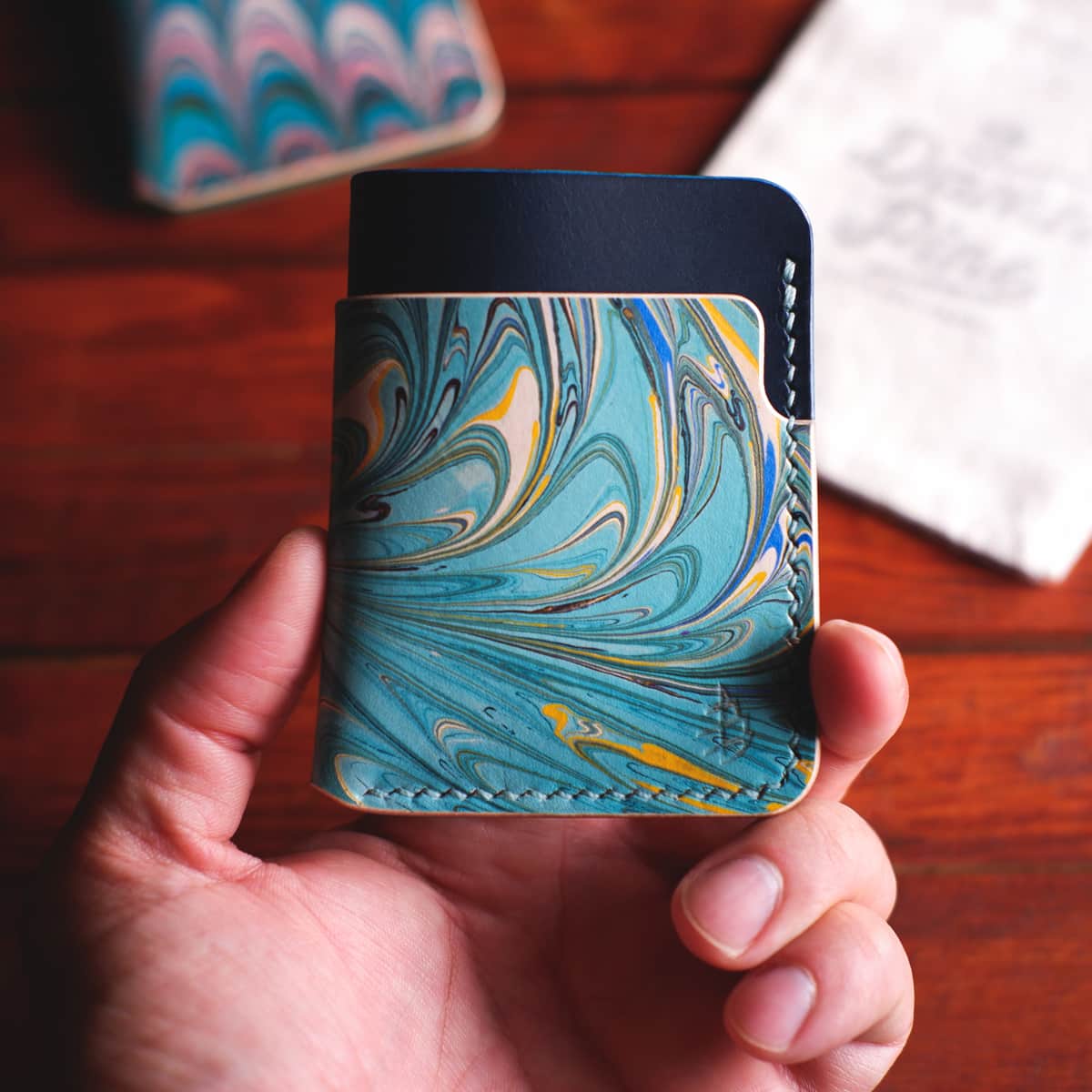 The Vertical Card Holder in Blue Buttero and hand dyed marbled vegetable tanned leather held in hand
