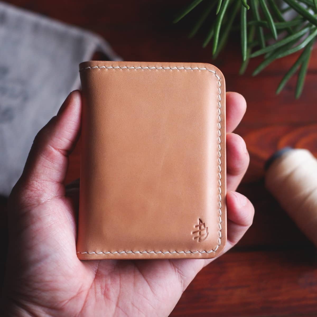 The Mountain Bifold wallet in Natural Vachetta held in hand