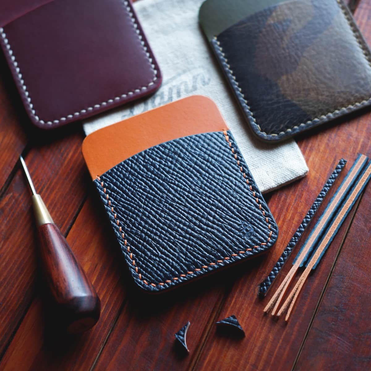 Tabletop view of three The Palm Card Holders in different leather combinations