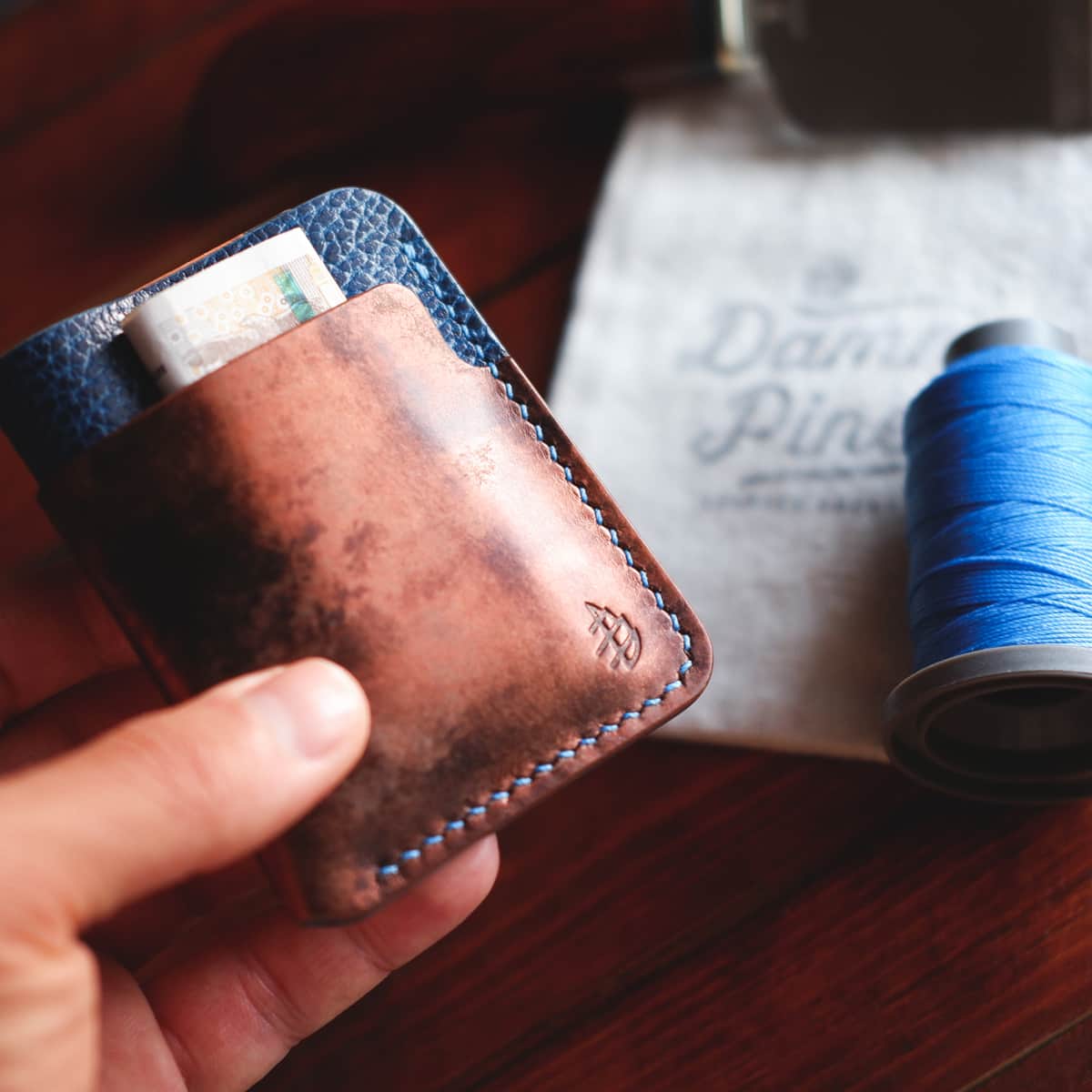 The Vertical Card Holder in Rame Bisanzio and Blue Tartufo full grain vegetable tanned leather held in hand